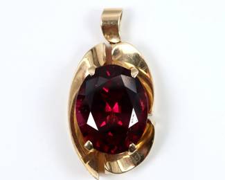 A 14k Gold and Rhodalite Garnet pendant.  Features an oval cut prong set Garnet approx. 10 1/2 x 16 mm, on a scrolled pendant with openwork design.  Marked "14k" and "FYKim" maker's mark, attributed to Frank and Kim of Yanke Designs, Traverse City, MI.  11.9 grams total.  Some surface wear.  Size 6 1/4.
