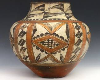 An early 20th century Native American Earthenware olla, likely Acoma Pueblo.   Large bulbous form with geometric polychrome decoration.  Some wear to decoration and surface flakes, deeper flake near foot.  Approx. 12" diameter x 11" high.