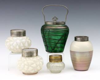 Five turn of the century Art Glass vessels with metal fittings.  Includes a Green biscuit jar with threaded decoration attributed to Pallme-Konig, an Iridescent White vessel with Purple threaded decoration, a pair of Iridescent White vases attributed to Kralik, and a small Iridescent posy vase.  Some wear, minor losses to threaded decoration, posy vase with replaced collar.  Up to 6 1/2" high.  
