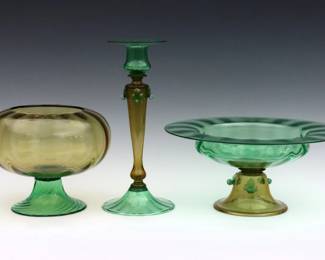 Three pieces of early 20th century Art Glass attributed to Steuben.  Each in Pomona Green and Amber glass, includes two center bowls and a candlestick, two with "mica flecked" technique.  Minor surface wear and scratches, a linear burst air bubble along top rim of larger bowl.  Up to 12 1/2" diameter and 12" high.