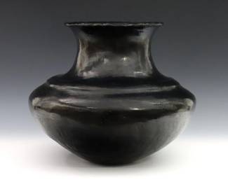 An early 20th century Native American Earthenware jar.  Bulbous form with scalloped rim and polished Black glaze.  Repaired rim and neck, some surface wear.  Approx. 11" diameter x 11" high.