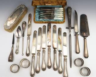 Twenty-five Sterling Silver and Silverplate items.  Includes a set of eight Sterling hollow handle spreaders by Dominick & Haff, a three piece Sterling hollow handle meat carving set, Sterling and Silverplate napkin rings, a Sterling brush, a set of six Mother of Pearl fruit knives with Silverplate blades, and others.  Each marked or tested.  Some wear and damage, many monogrammed.  Up to 13 1/2" long.