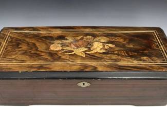 A turn of the century Swiss cylinder music box.  Mixed wood case with inlaid floral top and grain-painted sides, includes an 11" cylinder with multiple tunes.  Some exterior wear and minor damage, not properly winding.  20 1/2 x 8 1/2 x 5 3/4" high overall.