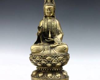 A Chinese weighted Brass figure of Guan Yin.  Depicted seated on a Lotus plinth with characters along the front.  Some pitting and build-up.  18" high.  