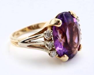 A 14k Gold, Amethyst and Diamond ring.  Features an oval cut prong set Amethyst stone approx. 9.5 x 12 mm, flanked by six Diamond accents each approx. 1.5 mm, on a band with fluted detail.  Marked "14k" and "37".  6.1 grams total.  Slight surface wear.  Size 5 1/4.