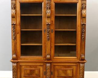 An early 20th century Italian Renaissance Revival Period bookcase.  Walnut construction features a molded crown with dentil detail over two glass doors with figural pilasters and floral detail, two lower doors with Acanthus leaf pilasters on scrolled feet.  Restored finish with only slight wear.  Knocks down for moving.  60 x 18 x 83" high overall.