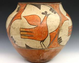 An early 20th century Zia Pueblo Earthenware olla.  Large bulbous form with polychrome geometric and bird decoration.  Two chips to rim, some wear to surface and decoration.  Approx. 16" diameter x 13 3/4" high overall.  
