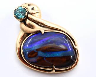 A 14k Gold necklace pendant with Iridescent gemstone and Blue Topaz.  Features a prong cut cabochon, likely a Boulder Opal, with Blue, Green and Brown tones approx. 13 x 18 mm, in a scrolled mount with a round cut prong set Blue Topaz approx. 4 mm.  Marked "14k".  7.8 grams total.  Minor surface wear.  1 1/8" high.
