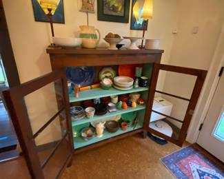 Wood and glass farmhouse cabinet, pottery and dishes