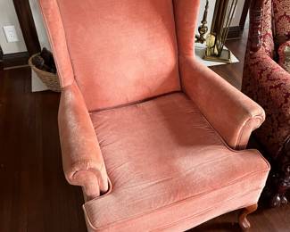 One of two matching pink upholstered wingback armchairs.