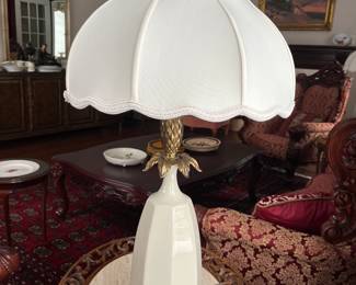 One of two matching Hollywood Regency cream ceramic and brass pineapple table lamps.
