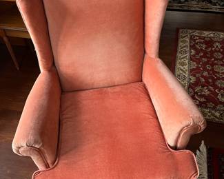 One of two matching pink upholstered wingback armchairs.