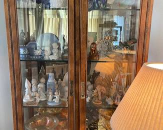 This display cabinet is lighted and has a mirror background with glass shelves. Precious moments, Wedgwood, Nativities, Art glass,  Fenton Carnival