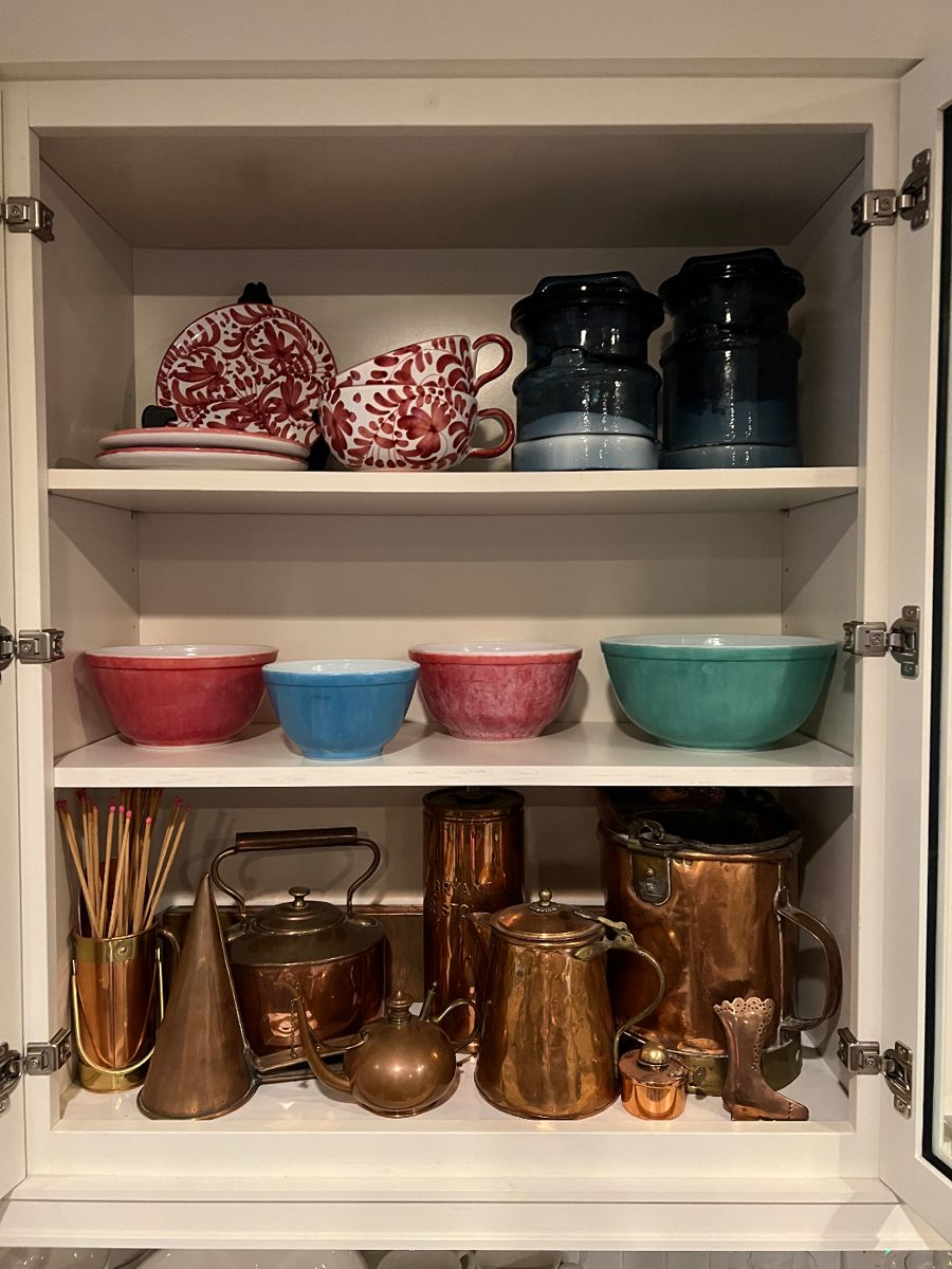 The top shelf has Italian pottery, The middle shelf has vintage Pyrexx. And the bottom shelf has a wonderful collection of copper.