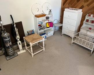 Along with the vintage children's furniture, a pair of vacuum cleaners, a small bookcase, and a wooden rattan seat.
