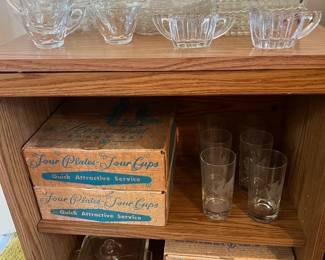 More glasses (or Waterford crystal) are on the table above the four boxes of Homestead plates and cups.