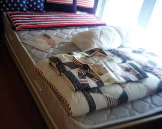 Twin bed.  Maple frame.  R/W/B bedding, pillows 