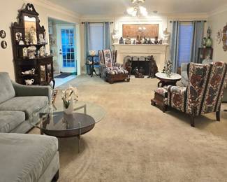Furnishings include several antique/vintage curio cabinets, 2 wingback chairs with wood-base ottomans, 2 powder blue couches, various occasional tables, end tables, coffee tables, etc