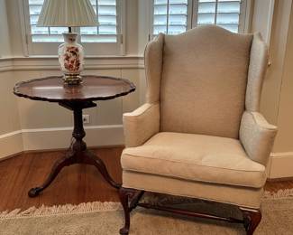 Nice cream wingback easy chair with a Baker Historic Charleston carved chippendale mahogany pie crust tilt top table.
