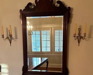 Hand carved mahogany mirror flanked by brass sconces.