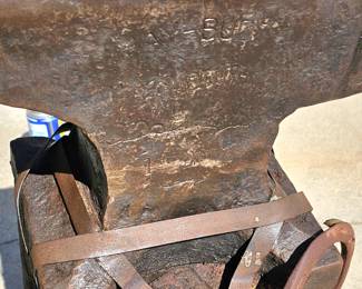 Large, heavy vintage anvil strapped on an old block of wood.