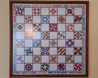 Framed cross stitch depicting various quilt patterns
