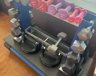 Workout room, which includes a power rack cage, weights, power bars, resistance bands, kettlebells, dumbbells, a treadmill, benches, and essential stretching equipment.
