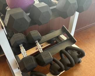 Workout room, which includes a power rack cage, weights, power bars, resistance bands, kettlebells, dumbbells, a treadmill, benches, and essential stretching equipment.