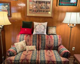Living room accessories, including love seat couch, throw pillows, floor lamps, and artwork.