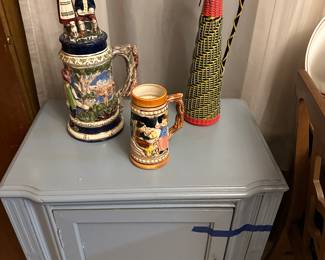 A beautiful little wooden Side Cabinet! Painted Battle ship gray! Also some vintage steins and a Brazilian Wine bottle. 