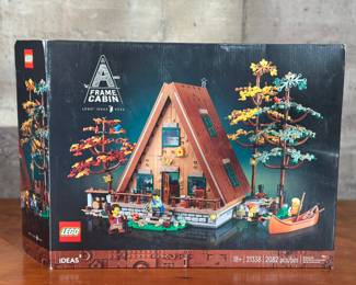 An adult-owned (built-once) Lego Ideas #046, A-Frame Cabin set. Confirmed as a complete set, guaranteed by Salem Auction House with all the original packaging. Lego 21338 Ideas A-Frame Cabin Building Toy Set is ideal gift for birthday, holiday or surprise gift to a lover of the great outdoors, nature, architecture or building. The iconic, steeply angled roof is easily detached for access to the detailed interior. The bedroom on the upper level and the living area, study and kitchenette on the lower level are full of accessories to create a cozy atmosphere. The set also includes 3 colorful trees that can be connected to create an island, plus a canoe. With 4 customizable minifigures and 11 animal figures. The buildable A-Frame Cabin model measures over 9.5 inch high, 8 inch wide and 9 inch deep.