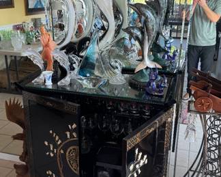 Just a few of the many blown glass & crystal dolphin figurines atop an oriental bar station.