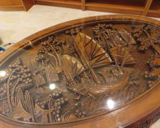 Highly carved Asian themed oval coffee table with glass top.