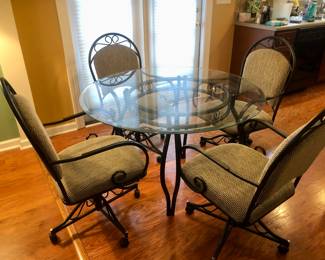 Glass top table with 4 tan/grey chairs on wheels