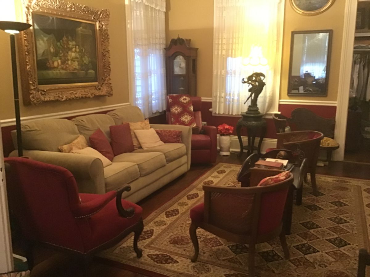 Red velvet chairs, grandfather clock, sleeper sofa, red swivel rocker, rugs, art, rugs, lamps