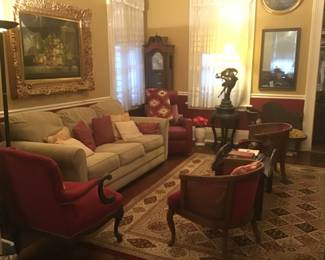 Red velvet chairs, grandfather clock, sleeper sofa, red swivel rocker, rugs, art, rugs, lamps
