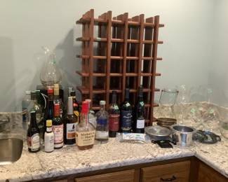 Several bottles of alcohol, wooden wine rack, clear glass vases