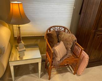 rattan chair with caned seat, decorative pillows.