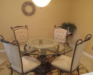 Round glass and metal table with upholstered chairs