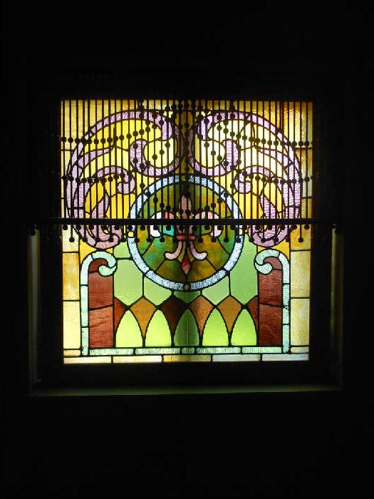 Stained Glass with Fretwork hanging in front of glass item