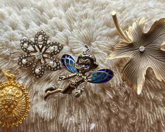 A collection of various gold pins and pendants.