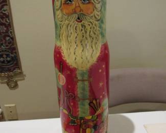 Tall wooden Santa holds a wine bottle.