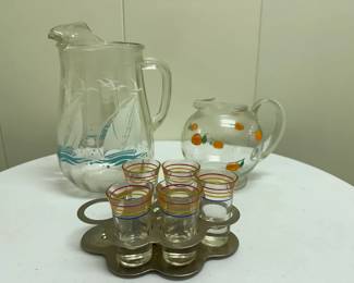 (9pc) "Colorful" Motif Glassware | 
 Glassware with "colorful" (oranges, ships, etc.) motifs including: Pitcher with oranges motif
Pitcher with ships motif
5 striped shot glasses (missing one) and silver carrying tray
