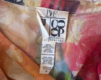 Closeup of Diane von Furstenberg silk floral print blouse size 8 with beaded tie at V neck and 3-button closure at front. Cuffs with single-button closure and ruching. 3/4 dolman sleeves.