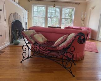 A vintage wrought iron swoop bench with rolled arms and scroll work