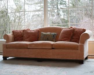 A lovely rolled arm three seat camelback sofa in soft peach upholstery, with throw pillows