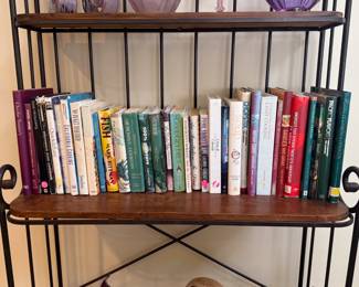 A baker's rack with wooden shelving units, beautiful art glass and ceramics, and lots of cookbooks!