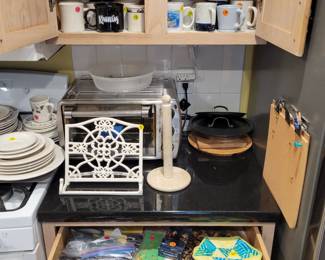 Mugs, cast iron cookbook holder, Oster toaster oven, Misc kitchen items.