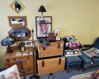 Upholstered Antique denim covered chair and ottoman. Wicker chests, art work, lamps.