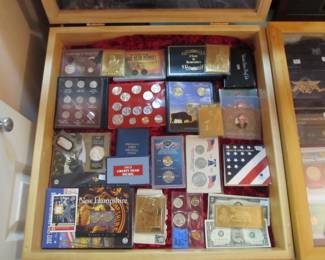 Lots of uncirculated collector coin sets and some gold baseball cards.